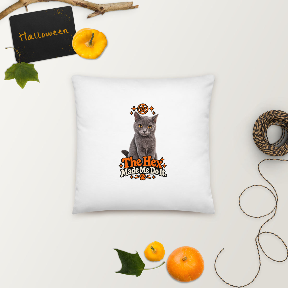 White Halloween cat throw pillow featuring Uno and the orange “The Hex Made Me Do It” design, styled with autumn leaves, pumpkins, and Halloween decorations.