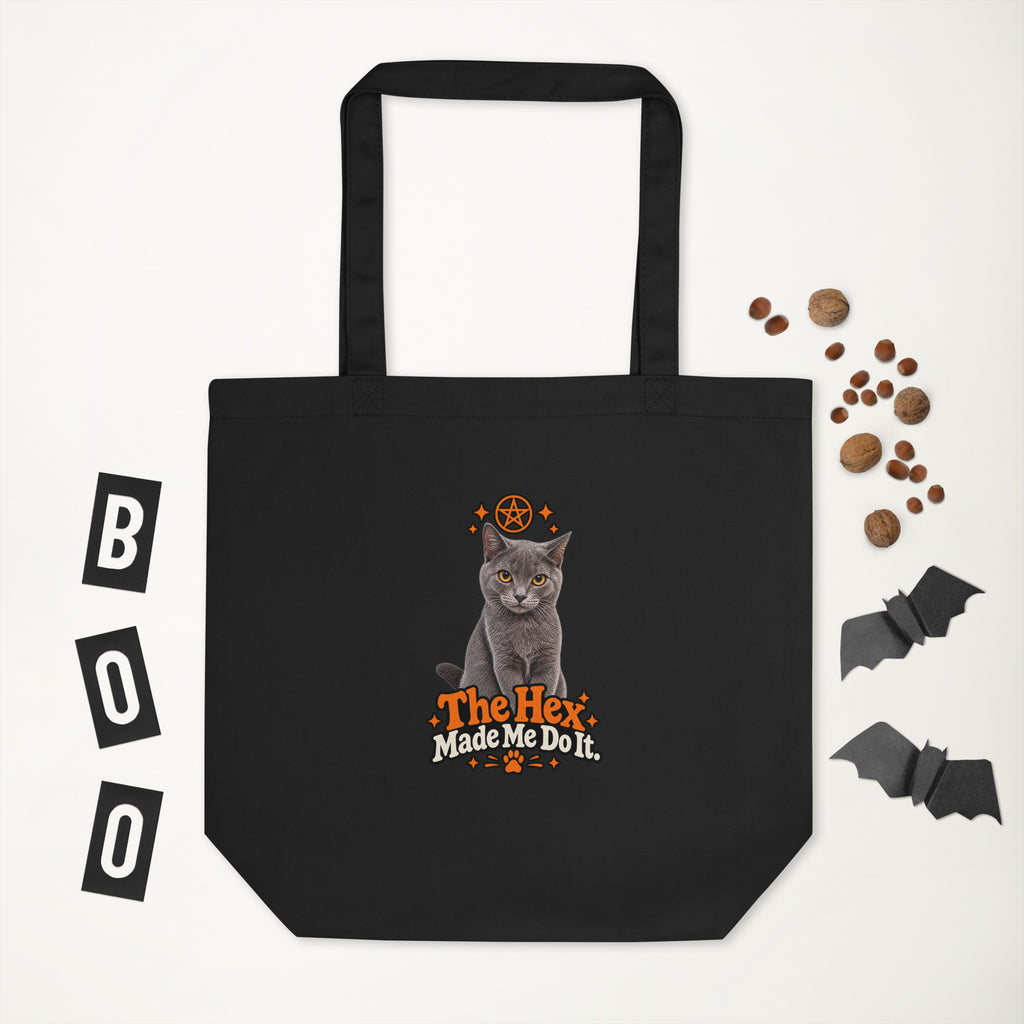 Black Halloween tote bag with the Uno the Cat design and “The Hex Made Me Do It” slogan, displayed against a white background with decorative bats and autumn nuts.
