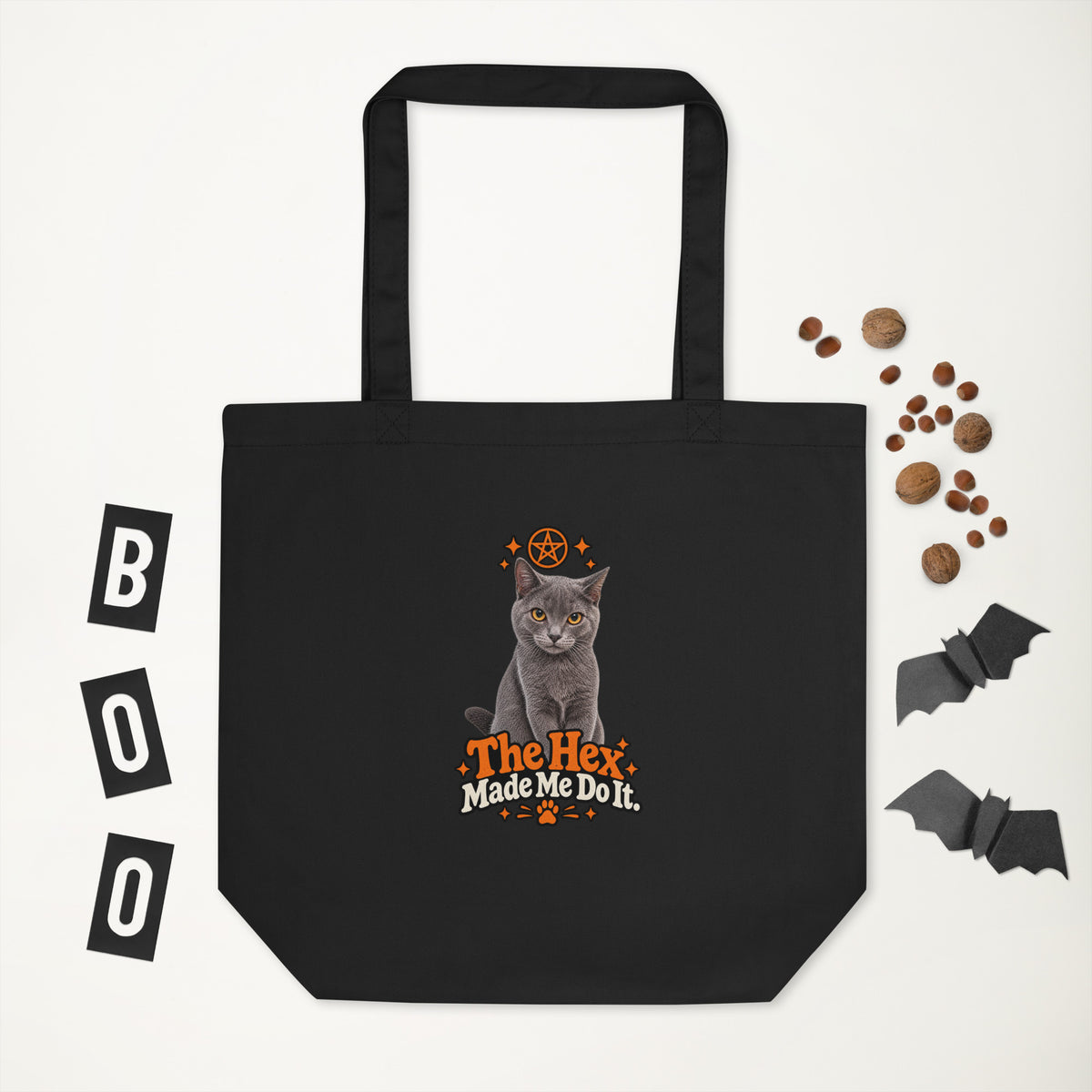 Black Halloween tote bag with the Uno the Cat design and “The Hex Made Me Do It” slogan, displayed against a white background with decorative bats and autumn nuts.