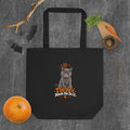 Black Uno the Cat Halloween tote bag featuring a gray cat, orange pentagram and stars, paw print, and “The Hex Made Me Do It” slogan, styled with pumpkins and Halloween decorations.