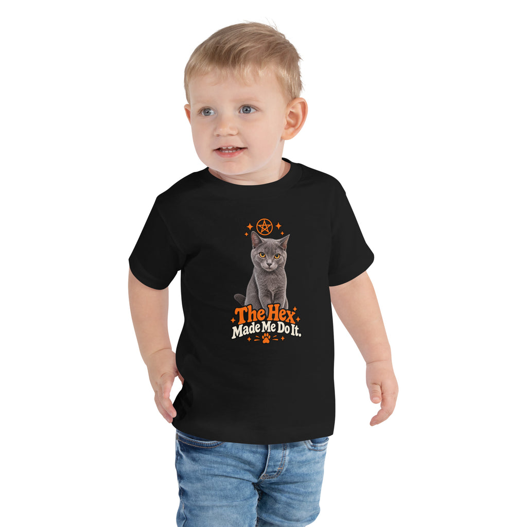 Toddler wearing a black Halloween cat T-shirt with Uno the gray cat, orange star accents, and the playful “The Hex Made Me Do It” slogan.